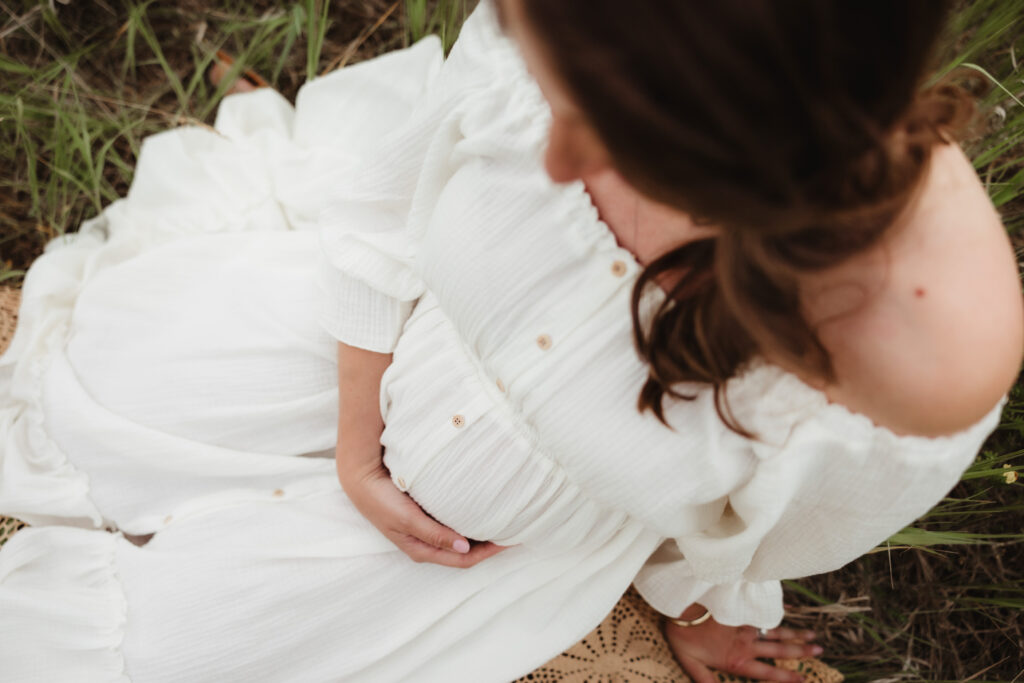 An expectant mother cradles her growing belly during her maternity session. Read on to learn when to book maternity photos.