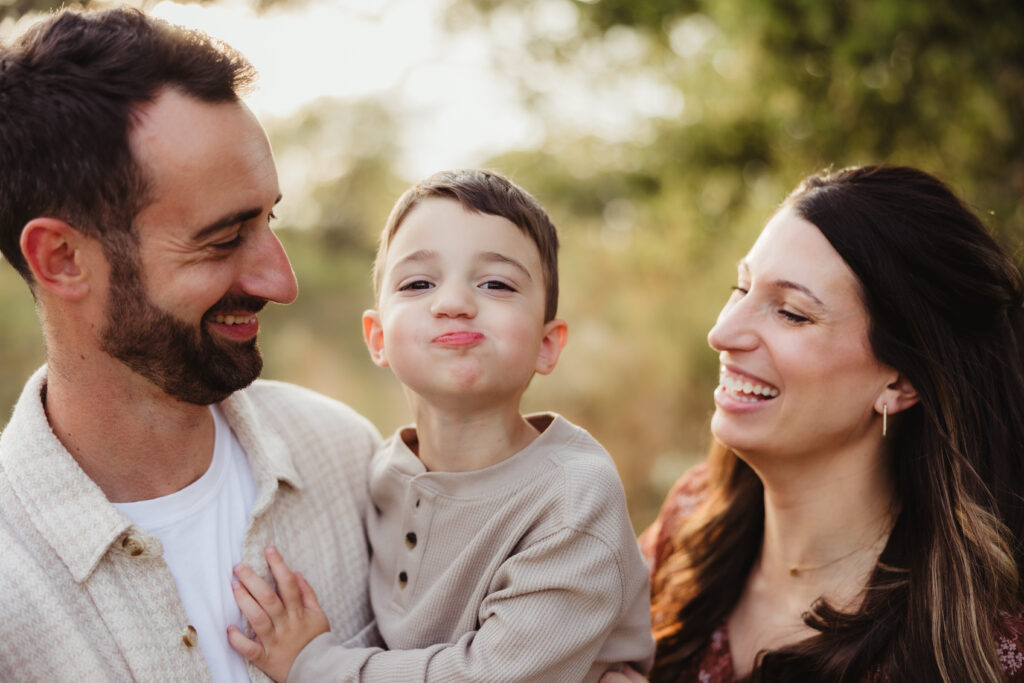 A family of three laughs together during their photo session. Photo taken by Sun Prairie Photographer, Elizabeth Pachniak Photography.