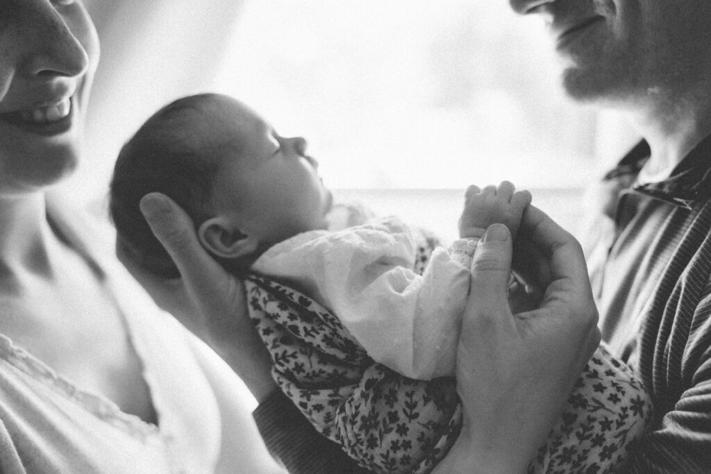 Newborn baby peacefully sleeping in her mom and dads arms, captured by a Sun Prairie Newborn Photographer, Elizabeth Pachniak Photography.