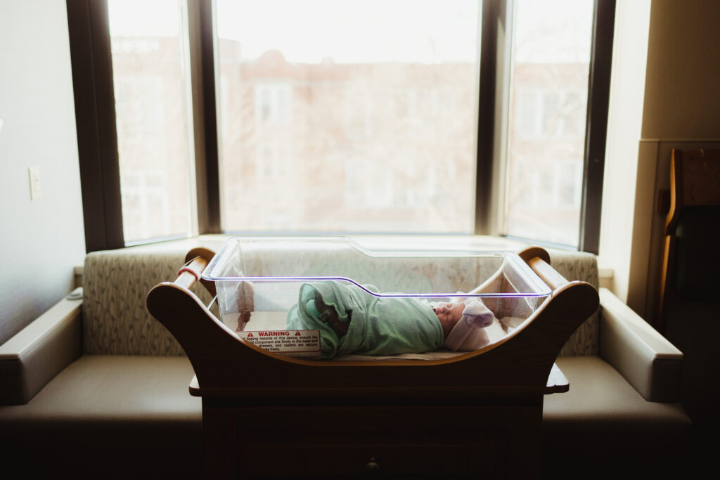 Newborn baby peacefully resting in a hospital room, showcasing the caring environment where Madison midwives support families during their childbirth journey.