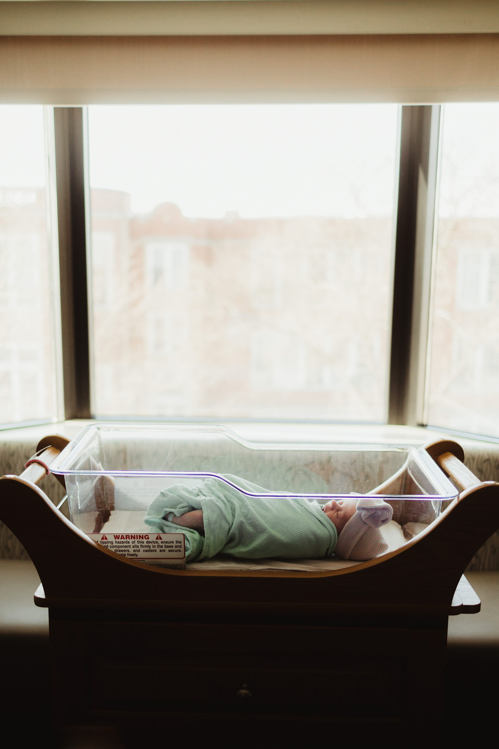 Newborn baby peacefully resting in a hospital room, showcasing the caring environment where Madison midwives support families during their childbirth journey.