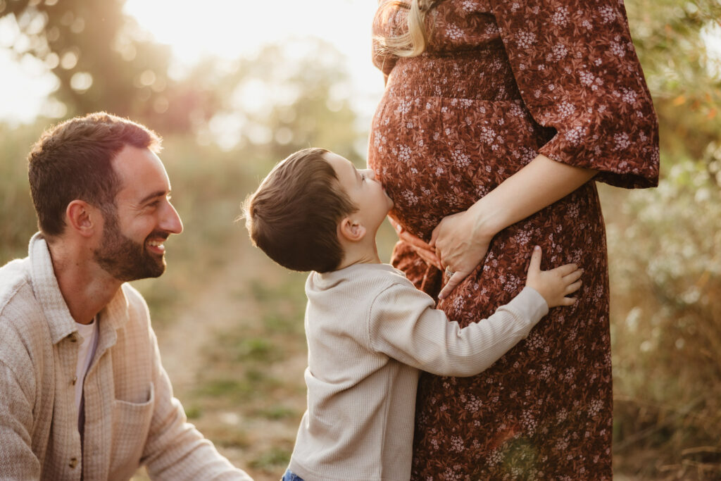 A toddler boy kisses his moms pregnant belly during their family photography session by Sun Prairie Photographer, Elizabeth Pachniak Photography.