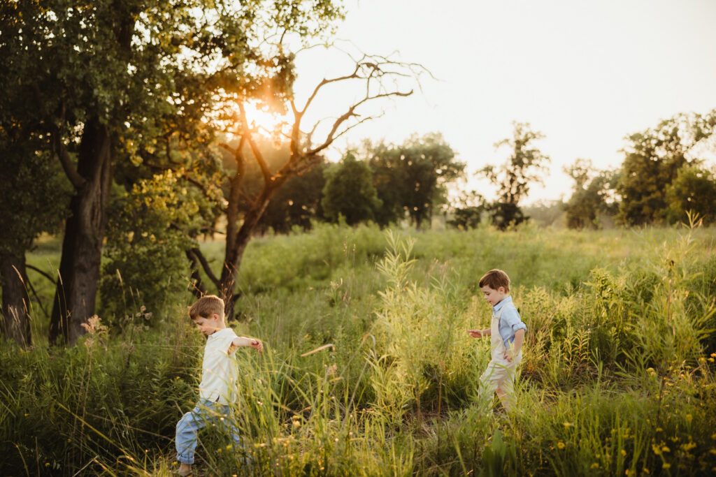 Madison WI Family Photographer 891A1069 Two little boys skip down a hill with arms out like an airplane as the sunsets during their family photography session in Madison WI.